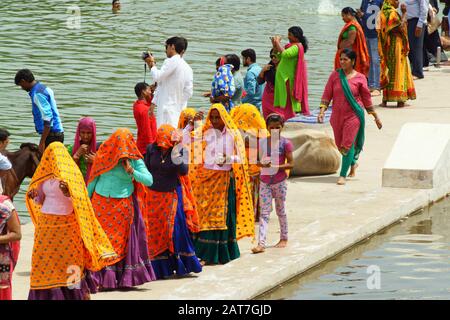 Pushkar, India - 15 agosto 2016: Uomini, mucche e donne in variopinti sari al lago per il bagno santo. Il lago Pushkar è uno dei luoghi più santi per gli indù Foto Stock