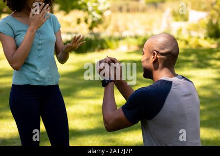 Giovane uomo che fa la proposta di matrimonio nel giardino Foto Stock