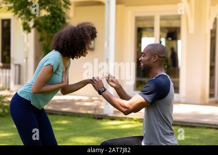 Giovane uomo che fa la proposta di matrimonio nel giardino Foto Stock