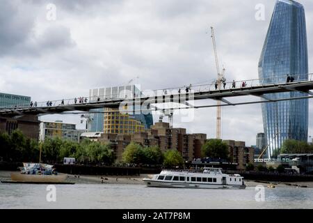 Una vista del fiume Tamigi scorcio, con l'edificio Walkie Talkie sullo sfondo, mentre una barca turistica passa sotto il ponte Millennium. Il Tamigi è un luogo popolare per i fangarking e i reperti archeologici. Foto Stock