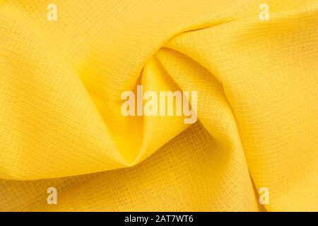 Sfondo astratto di tessuto giallo brillante. Pieghe, pieghe di tessuto di cotone. Modello del materiale, struttura del tessuto. Onde sullo sfondo Foto Stock