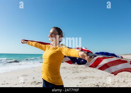 Donna con bandiera americana sulla spiaggia Foto Stock