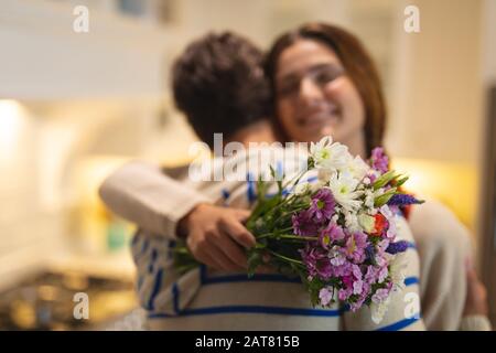 Giovane uomo che dà un bouquet di fiori alla giovane donna Foto Stock