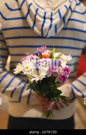 Giovane uomo che nasconde dietro la schiena un bouquet di fiori Foto Stock