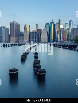 Lower Manhattan Skyline da Brooklyn Bridge Park Old Pier 1 con un arco Di Pylons Simmetrico Curva nel fiume Est durante l'alba. Foto Stock