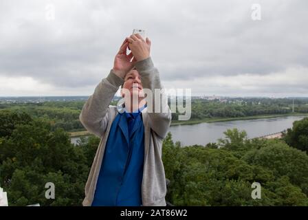 Selfie pericoloso. Una donna scatta un'immagine di se stessa con un telefono cellulare con un colpo grande. Foto Stock