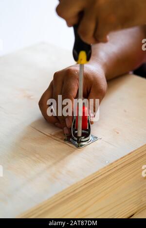 Fissaggio ruota orientabile su legno compensato, mobili. Foto Stock