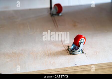 Fissaggio ruota orientabile su legno compensato, mobili. Foto Stock