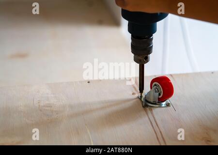 Fissaggio ruota orientabile su legno compensato, mobili. Foto Stock