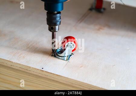 Fissaggio ruota orientabile su legno compensato, mobili. Foto Stock