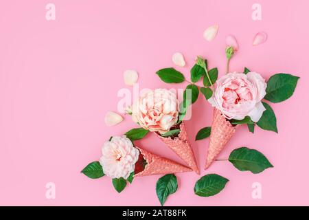 Gelato dai fiori di pony in un cono di cialda su sfondo rosa dall'alto, bella disposizione floreale, colore vintage, piatto lay. Cornice floreale con Foto Stock
