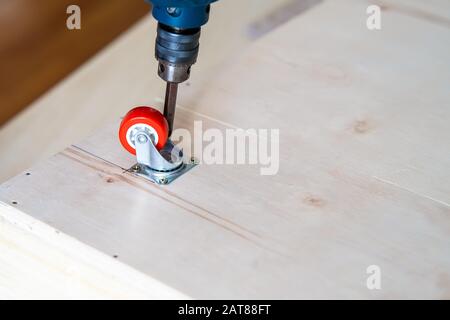 Fissaggio ruota orientabile su legno compensato, mobili. Foto Stock