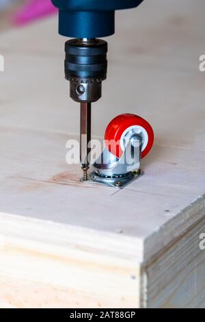 Fissaggio ruota orientabile su legno compensato, mobili. Foto Stock