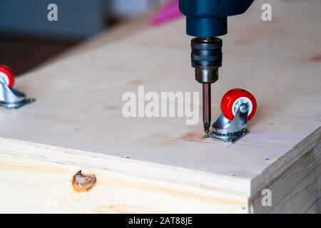 Fissaggio ruota orientabile su legno compensato, mobili. Foto Stock
