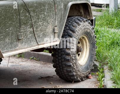 Ruote sporche e sospensione di un vecchio SUV parcheggiato Foto Stock