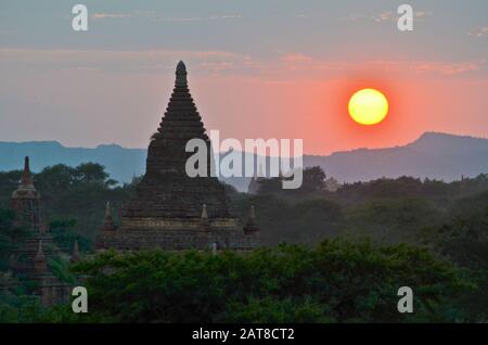 Tramonto su montagne lontane con stupa di tempio in primo piano, Bagan, Myanmar. Foto Stock