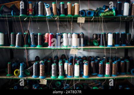 Primo piano di scaffali di filo colorato per cucire suole di scarpe in una fabbrica. Foto Stock