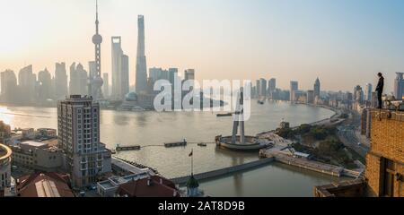 Uomo ammirando la vista sul fiume Huangpu e lo skyline di Shanghai al mattino presto, Shanghai, Cina Foto Stock
