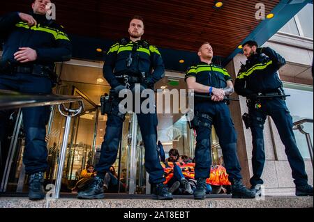 Polizia in guardia accanto a un gruppo di attivisti XR incollati alle porte di cristallo durante la campagna.Circa venti attivisti del gruppo Extinction Rebellion si sono mostrati nella sede della Shell come parte della campagna Shell deve cadere, che si sta svolgendo per tutta la settimana in tutto il paese. Alcuni degli attivisti della ribellione d'estinzione si sono incollati alle finestre e alle porte di cristallo dell'edificio. Dopo aver rifiutato di lasciare il posto, la maggior parte di loro sono stati arrestati dalla polizia. Foto Stock