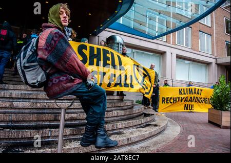 Un attivista XR seduto accanto a un enorme banner durante la campagna.Circa venti attivisti del gruppo Extinction Rebellion si sono presentati presso la sede Shell come parte della campagna Shell deve cadere, che si sta svolgendo per tutta la settimana in tutto il paese. Alcuni degli attivisti della ribellione d'estinzione si sono incollati alle finestre e alle porte di cristallo dell'edificio. Dopo aver rifiutato di lasciare il posto, la maggior parte di loro sono stati arrestati dalla polizia. Foto Stock