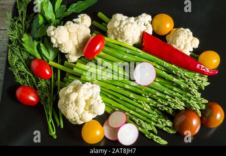 Insalata a disposizione piatta di verdure fresche su sfondo nero, primo piano Foto Stock