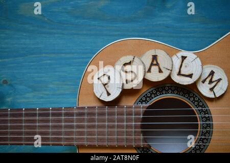 Chitarra su sfondo di legno teale con pezzi di legno su di essa scritta la parola: Salmi Foto Stock