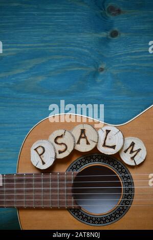 Chitarra su sfondo di legno teale con pezzi di legno su di essa scritta la parola: Salmi Foto Stock