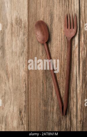 cucchiaio intagliato e forchetta su sfondo di legno con spazio copia Foto Stock