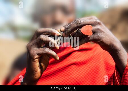 L'uomo africano che tiene una torta di smoldering nelle sue mani con un anello rosso del cuore. Tanzania, Africa. Messa a fuoco selettiva. Foto Stock