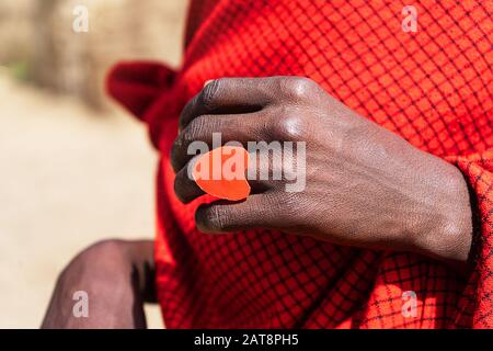 L'uomo africano che tiene una torta di smoldering nelle sue mani con un anello rosso del cuore. Tanzania, Africa. Foto Stock