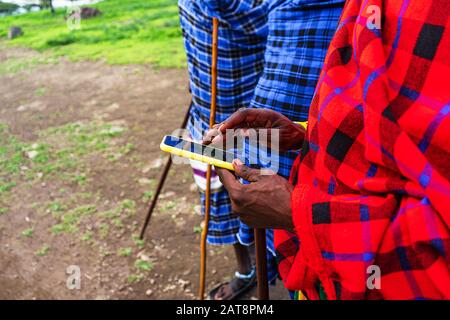 Uomo africano in abito tradizionale con un cellulare. Tanzania, Africa. Primo piano. Foto Stock