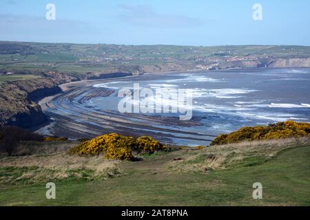 Una vista della Baia di Robin Hood e del Mare del Nord con bassa marea, North York Moors National Park, Yorkshire, Inghilterra, Regno Unito. Foto Stock