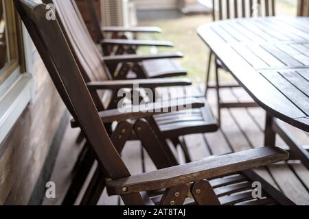 Sedie trasformabili in legno e un tavolo, marrone, si trovano sulla veranda aperta, nel cortile della casa, in una giornata estiva. Foto Stock