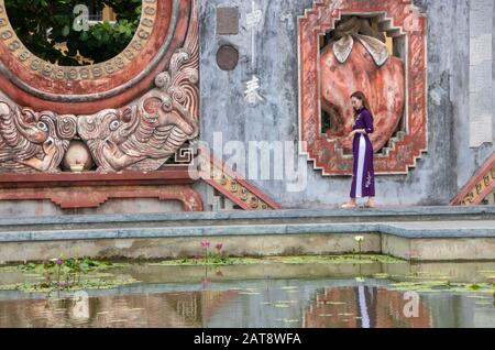Ad Hoi An, Vietnam , l'agosto 2019 - la ragazza che riflette nella fontana della porta Tam Quan, o tre porte d'ingresso, che conduce al vecchio complesso del tempio bu Foto Stock