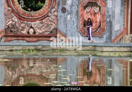 Ad Hoi An, Vietnam , l'agosto 2019 - la ragazza che riflette nella fontana della porta Tam Quan, o tre porte d'ingresso, che conduce al vecchio complesso del tempio bu Foto Stock