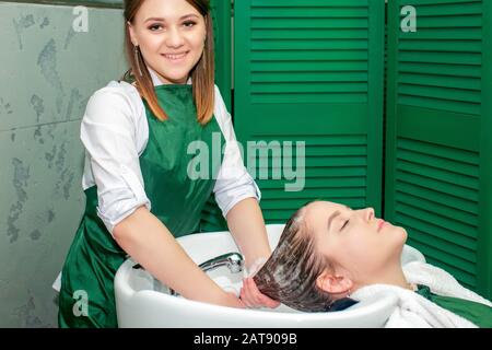 Parrucchiere lavaggio dei capelli della donna nel lavandino nel salone di bellezza. Foto Stock