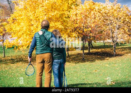 Un padre e figlio di età scolastica con badminton racchetta sta parlando Foto Stock