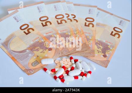 Lotto di farmaci in compresse e pillole accanto a cinquanta euro banconote sulla superficie bianca. Foto Stock