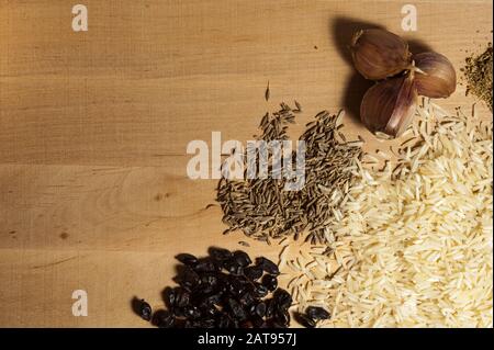 aglio, zira, frutti di bosco secchi e riso basmati su una tavola di legno Foto Stock
