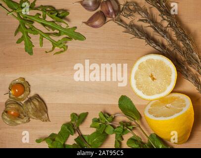 limone, aglio, rosmarino, aglio e altre spezie su una tavola di legno Foto Stock