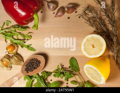 spezie e verdure su una tavola di legno con un cucchiaio di legno Foto Stock