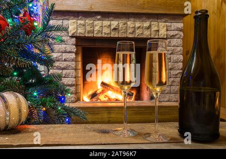 Vigilia di Natale. Accogliente camino. Champagne vino prima di Natale albero decorato giocattoli e luci di natale in casolare di campagna. Foto Stock