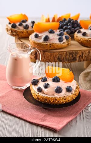 Vista ingrandita delle ciambelle dolci con yogurt, mirtillo e fetta di persimmon bianco sul tavolo di legno Foto Stock