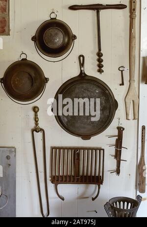 Abilità in ghisa d'epoca e vari utensili appesi su un muro in un negozio di antiquariato. Maine, Stati Uniti Foto Stock