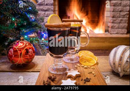 Accogliente scena di Natale con due bicchieri di VIN brulé su una tavola di legno prima di bruciare il camino. Foto Stock