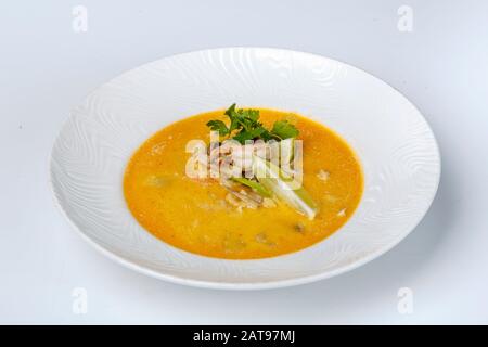 Zuppa di formaggio con gamberi. La zuppa gialla è decorata con limone e prezzemolo. Su sfondo bianco Foto Stock