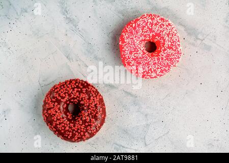 Deliziose ciambelle al cioccolato su una superficie grigia in cemento. Foto Stock