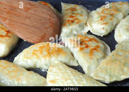 Gli gnocchi vengono fritti in padella. Piatto asiatico con una varietà di ripieni. Ryoza Fritto Foto Stock