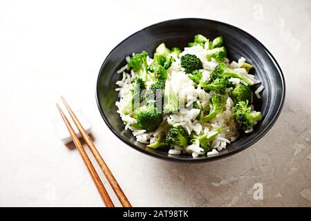 Riso cotto con broccoli fritti su sfondo di pietra brillante. Foto Stock