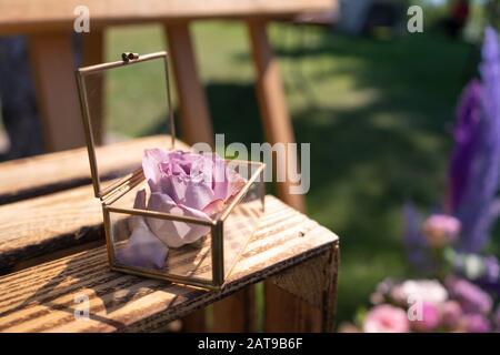 Scatola in vetro per anelli con una rosa viva all'interno. Foto Stock